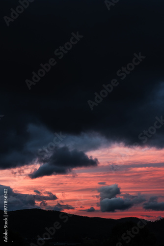 moody pink sunset with dark clouds over the hills