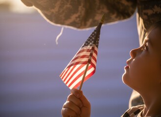 Small child holding American flag near soldier parent in golden hour light, young girl looking up with hope, military family and patriotism concept with copy space