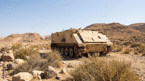 Abandoned M113 Armored Personnel Carrier in a desolate desert landscape with rocky hills.