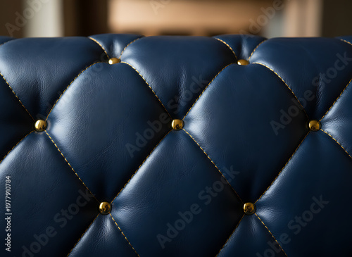 Deep navy blue quilted leather close-up shows diamond stitching and gold buttons. Elegant material forms a luxurious, plush background with rich texture suitable for premium interiors.Luxury Quilted T