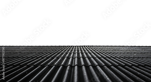 old corrugated asbestos roof tiles creating a dark weathered texture against a bright white sky.