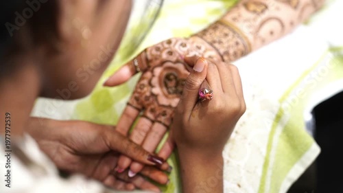 A girl drawing mehendi design on the hands of an Indian bride