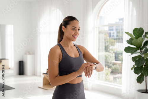 Free Download Smiling young woman checking a fitness tracker during a workout break at home - GFXLoad