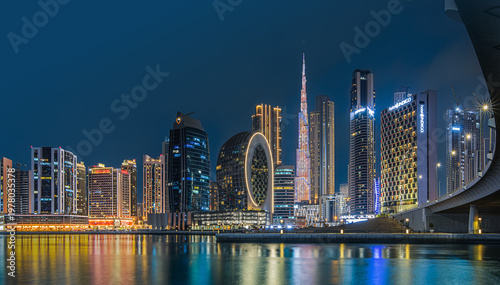 Modern buildings in the city center of Dubai in the evening. Illuminated skyscrapers in the financial center at the blue hour. View of skyline in united arab emirates at night and reflection
