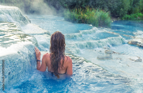 Photos Young woman relaxing in the turquoise thermal waters of Saturnia, Tuscany, Italy; natural hot springs and wellness spa concept
