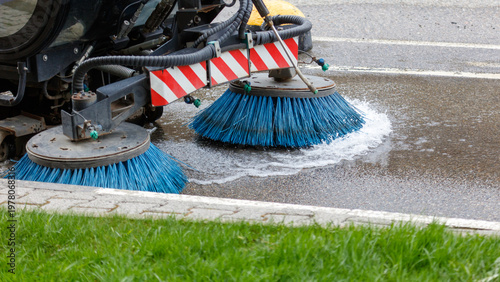 Blue bristles clean asphalt with water splash