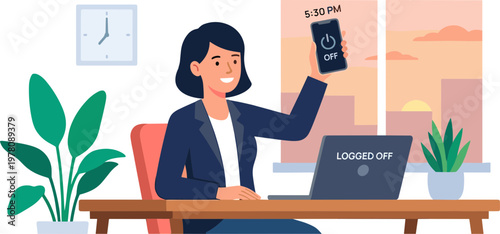 A woman sits at a desk in an office holding a phone and working on her laptop.