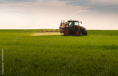 Tractor spraying wheat field with sprayer, herbicides and pesticides