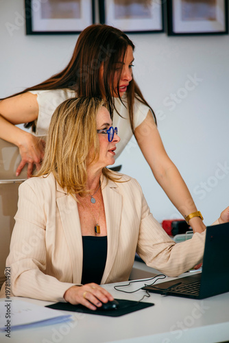 Business women collaborating on laptop in office environment