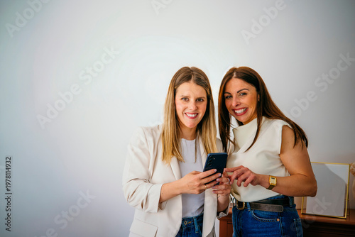 Women friends smiling using mobile phone technology