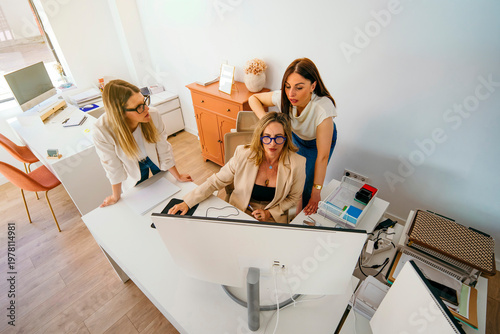 Businesswomen collaborating on computer, discussing project ideas at office