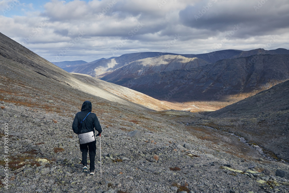 Fototapeta premium A tourist in a black jacket walks through the mountains