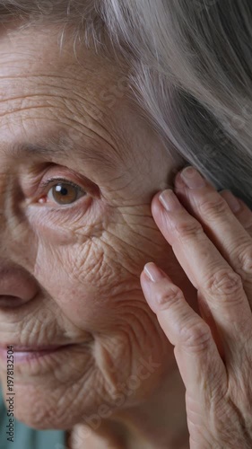 Close-up of elderly woman touching wrinkled skin near eye, vertical footage