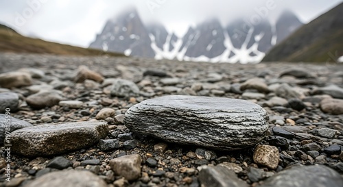 Scenic Landscape of Rocky Terrain with Mountains in the Background Under Cloudy Skies.