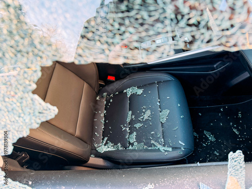 Car interior view through broken window with glass shards.