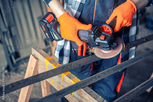 A man cuts metal using an angle grinder. Many sparks