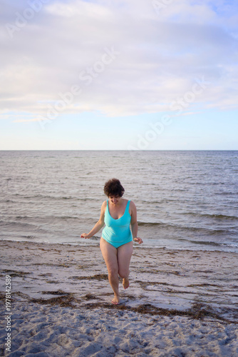  midsize woman in a turquoise swimsuit enjoying a bright life at the Copenhagen seaside