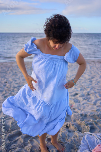 plus size woman changing clothes behind a pink scarf on a Copenhagen beach