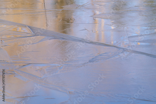 Φωτογραφία Intricate ice crystals on a frozen pond surface with tree reflections at sunrise