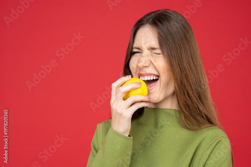 Surprised woman tasting fresh lemon grimacing from sourness