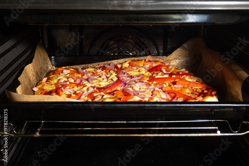 Homemade Pizza with Vegetables and Ham Baking in Oven on Parchment