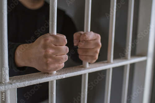 鉄格子を掴む刑務所の犯罪者　檻に閉じ込められた男性