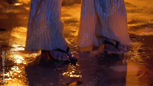 Woman's legs in heels dancing in outdoor. Female legs in heels dancing on a wet city street during rainfall at night. Concept of freedom, femininity, nightlife, and urban romance.