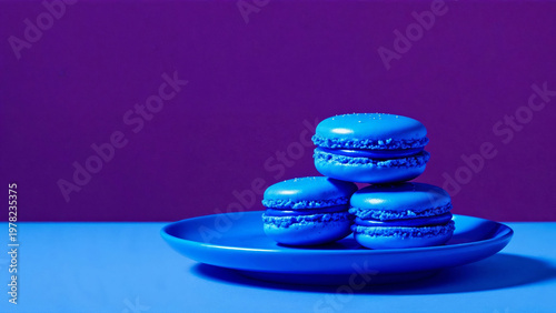 Blue macarons stacked on plate against purple backdrop