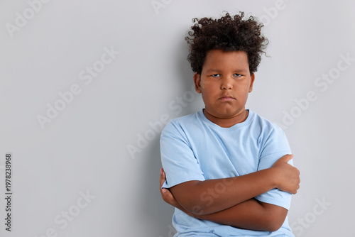 Photos Portrait of resentful little boy with crossed arms on light grey background