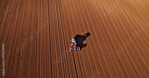 Aerial view of tractor sowing seeds in a plowed field