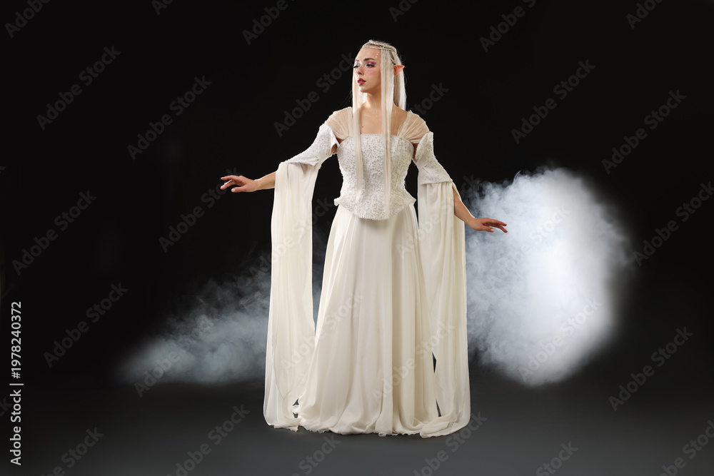 Naklejka premium Beautiful girl dressed as elf on black background with smoke