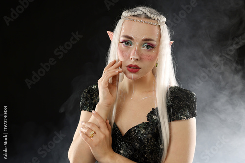 Foto Beautiful girl dressed as elf on black background with smoke