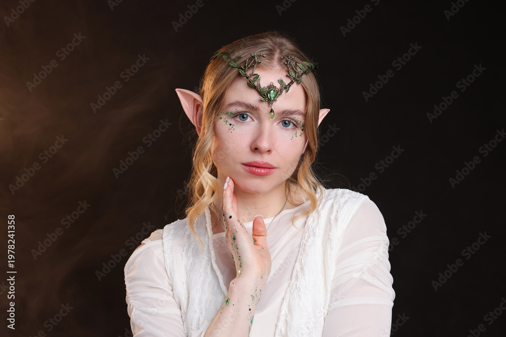 Naklejka premium Beautiful girl dressed as elf on black background with smoke