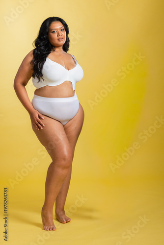 Canvastavla Female model standing and posing on yellow backdrop and floor wearing white bra