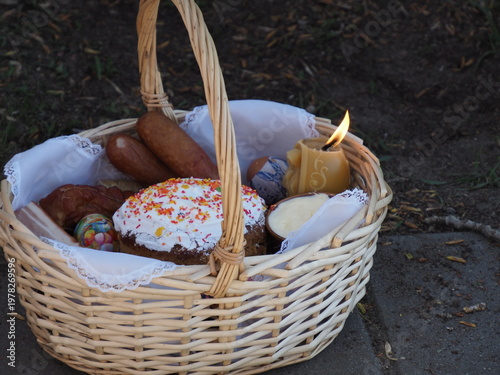 Detailed view of a burning yellow candle inside an Easter basket with festive food