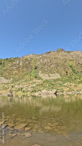 Calm Mountain Lake With Rocky Hills Under Clear Blue Sky