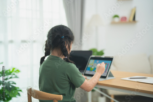 Young girl engaged in creative digital learning session at home using tablet for educational activities in bright and modern living space with natural light