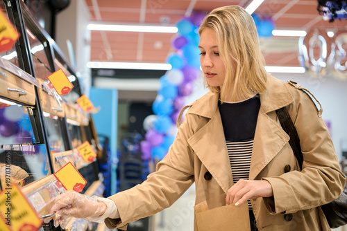 Canvas Print Woman shopping comparing food prices in supermarket inflation, price rising