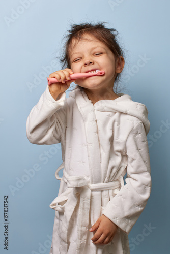 happy child girl brushing her teeth with eyes closed, promoting daily dental care and routine