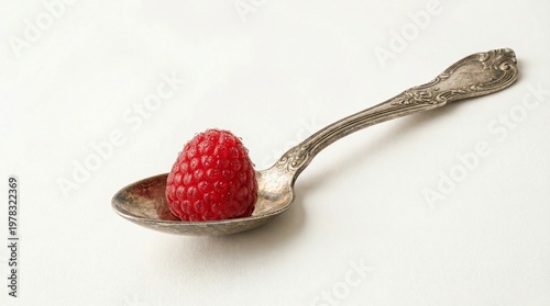 Fresh raspberry placed on vintage silver spoon against white background  