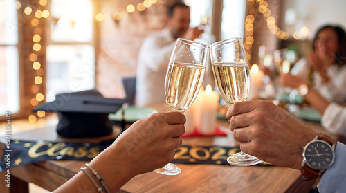 A couple toasting with champagne flutes at a graduation party with a cap and banner