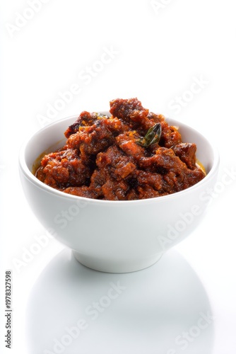 Spicy beef curry in a white bowl on a reflective surface