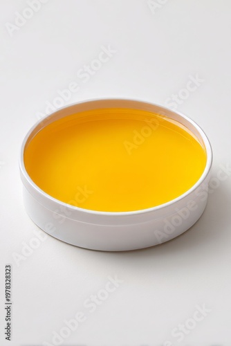 Bright yellow liquid fills a simple white bowl on a clean white background