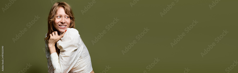Fototapeta premium Stylish young woman poses joyfully against a serene olive green backdrop