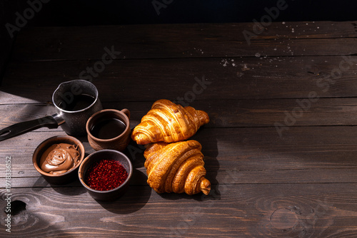 Morning breakfast with coffee, croissants, chocolate spread, and jam