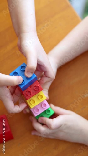The hands of two kids are shown in close-up as they assemble a construction set. Their collaboration and creativity bring their imaginative designs to life, one piece at a time. Vertical 4k footage.