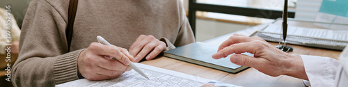 Foto Patient signing medical form while doctor pointing at paperwork during clinic vi