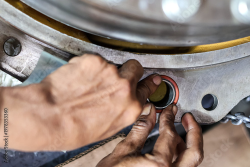 Canvas Print Close up of a mechanic installing orange rubber O-ring seals into a heavy metal industrial engine component in a workshop during a professional machinery maintenance