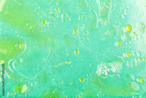 Water background with oil stains. Close-up view of water surface featuring oil stains and bubbles, creating abstract patterns. Blend of colors and textures, highlighting interaction of oil and water