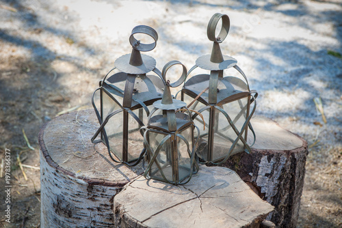 Antique iron lanterns displayed over tree trunks